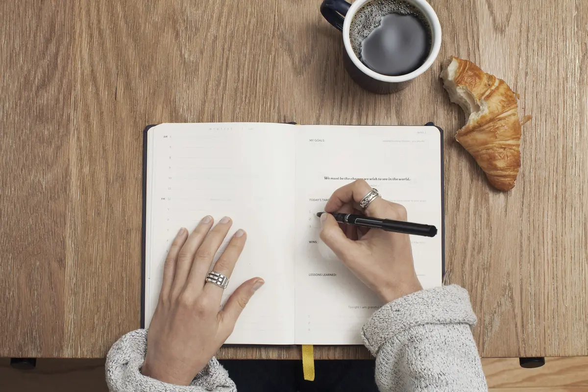 Mulher escrevendo em um caderno, como no registro de emoções usado na terapia