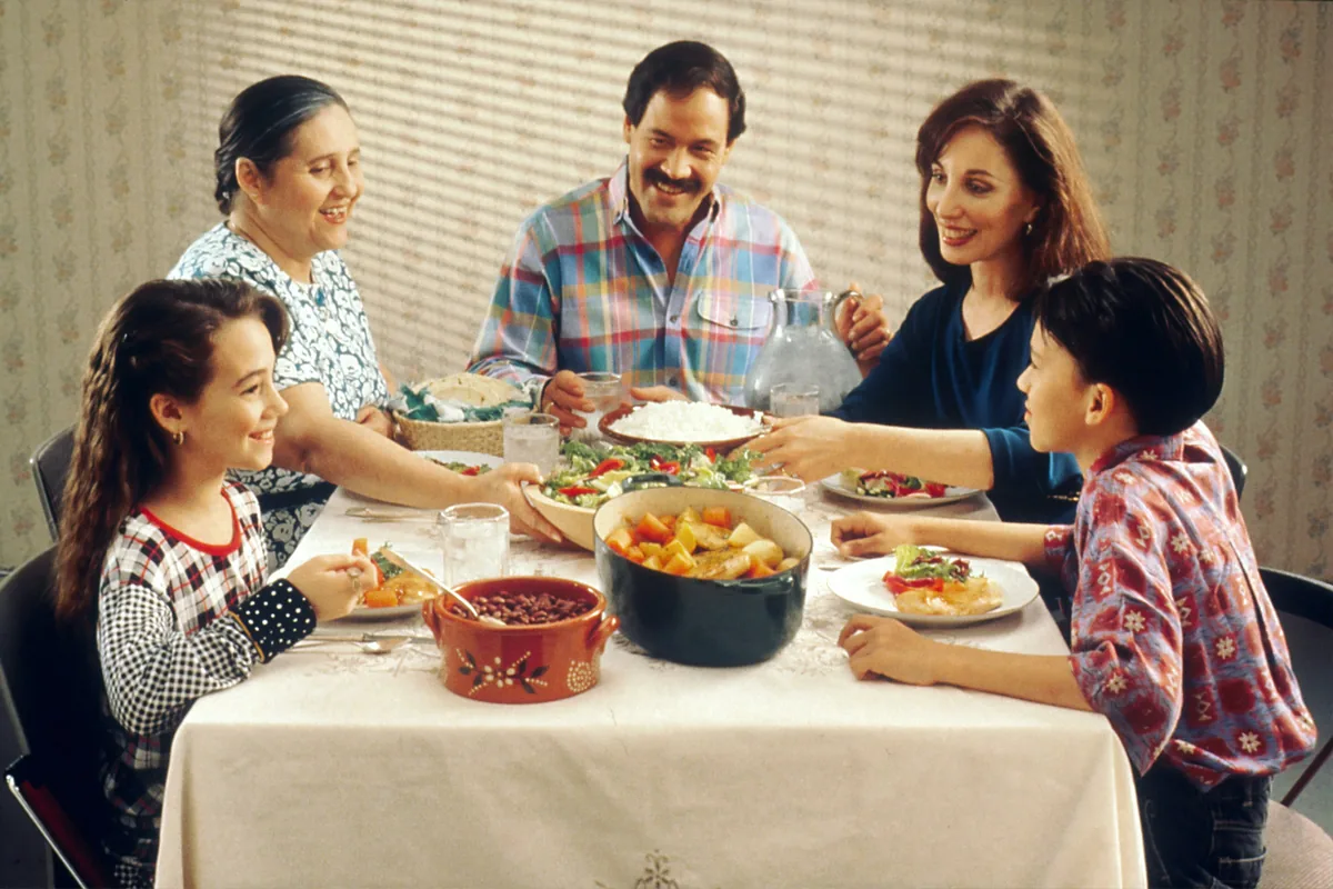 Família reunida à mesa em uma refeição caseira e variada, representando uma rotina alimentar regular